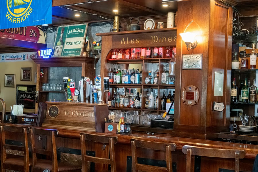 Warm interior of a traditional pub with a wooden bar and ale signs.