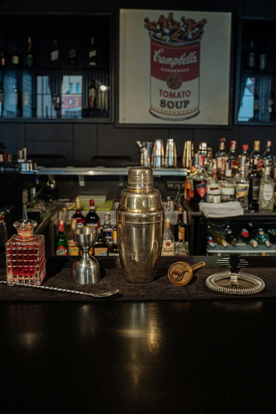Dimly lit cocktail bar with a wall of spirits behind the counter.