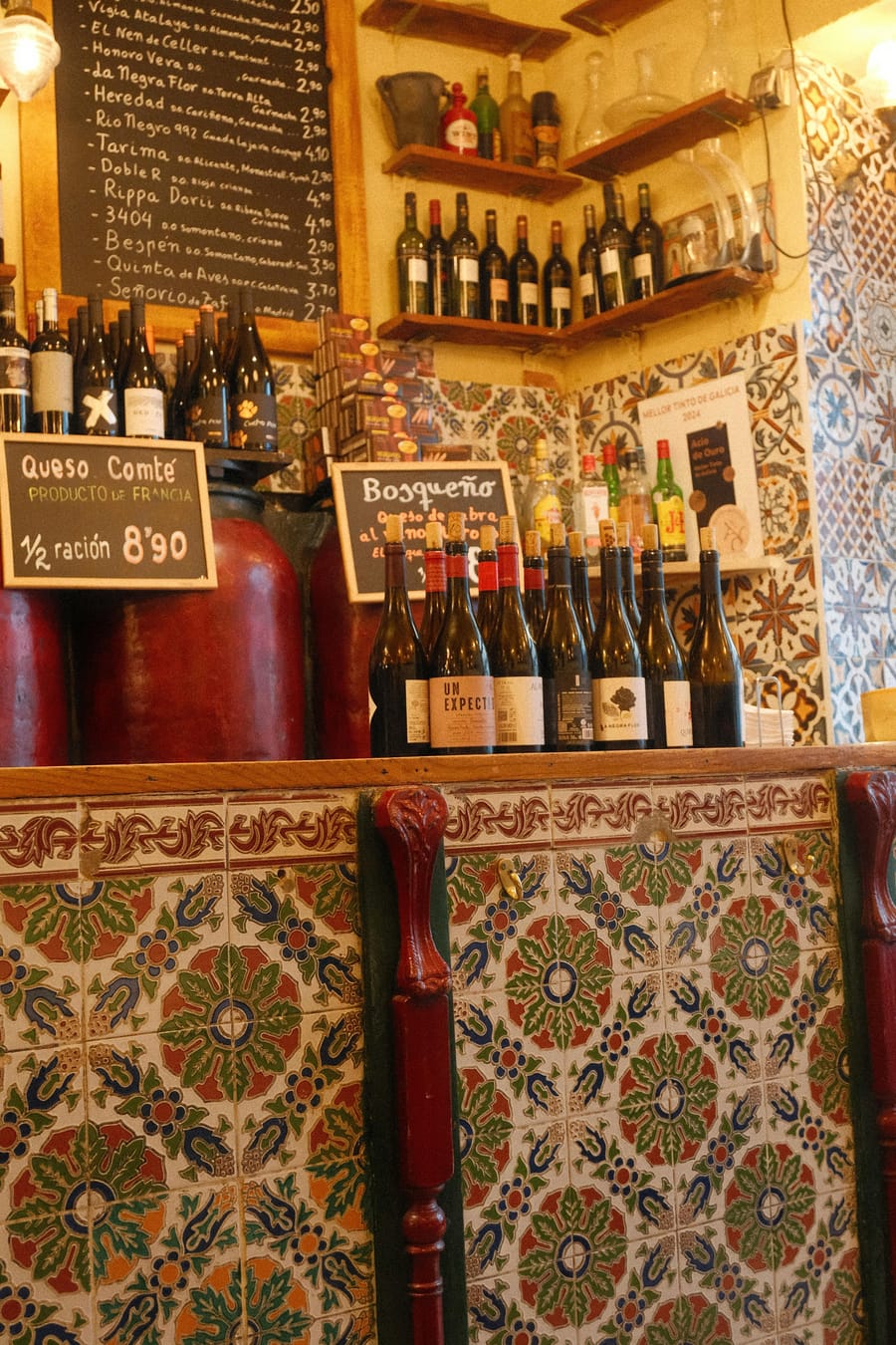 Cosy wine bar interior with tiled walls and bottles on display.