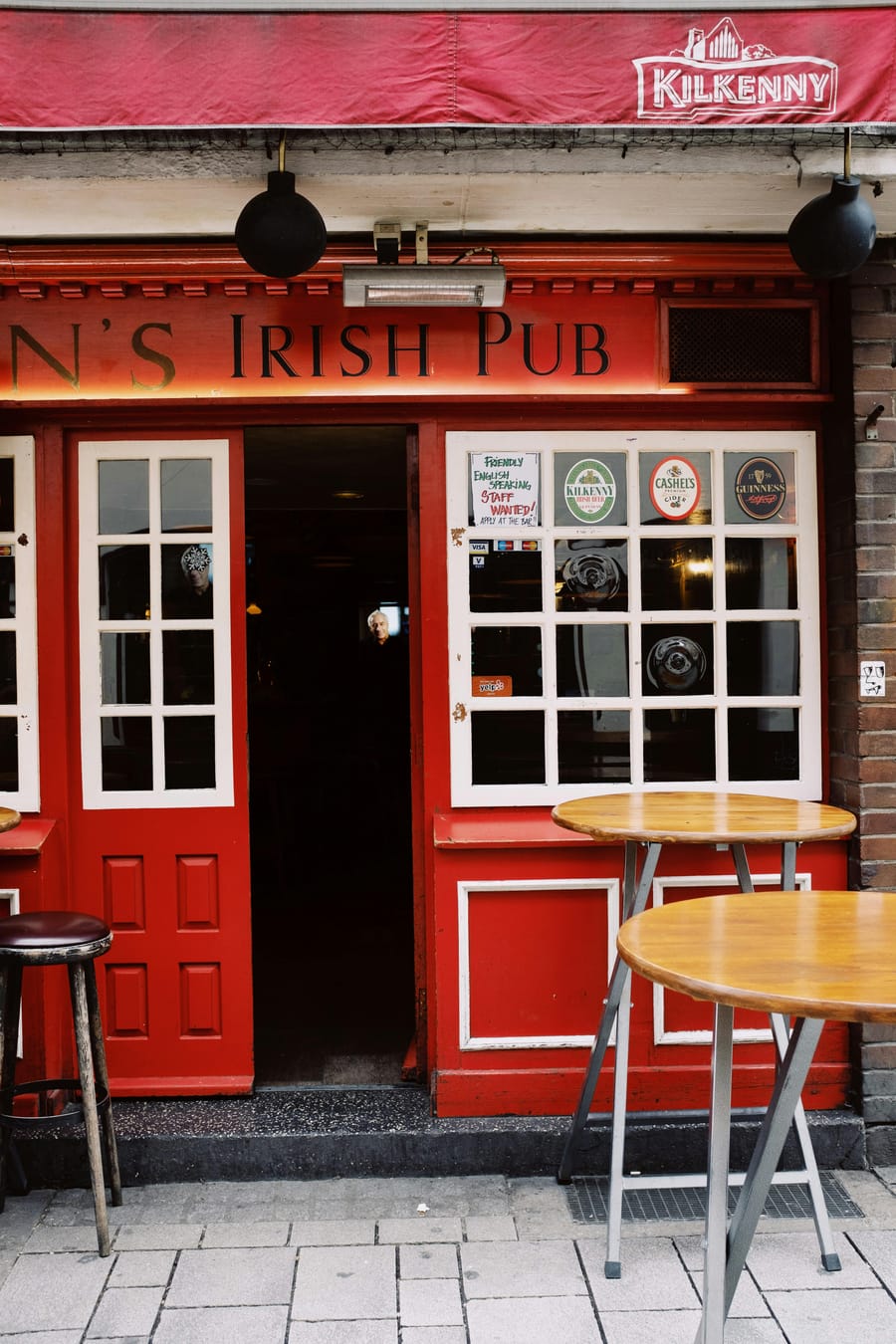 Entrance of an Irish-style pub with a bright red door and signage.