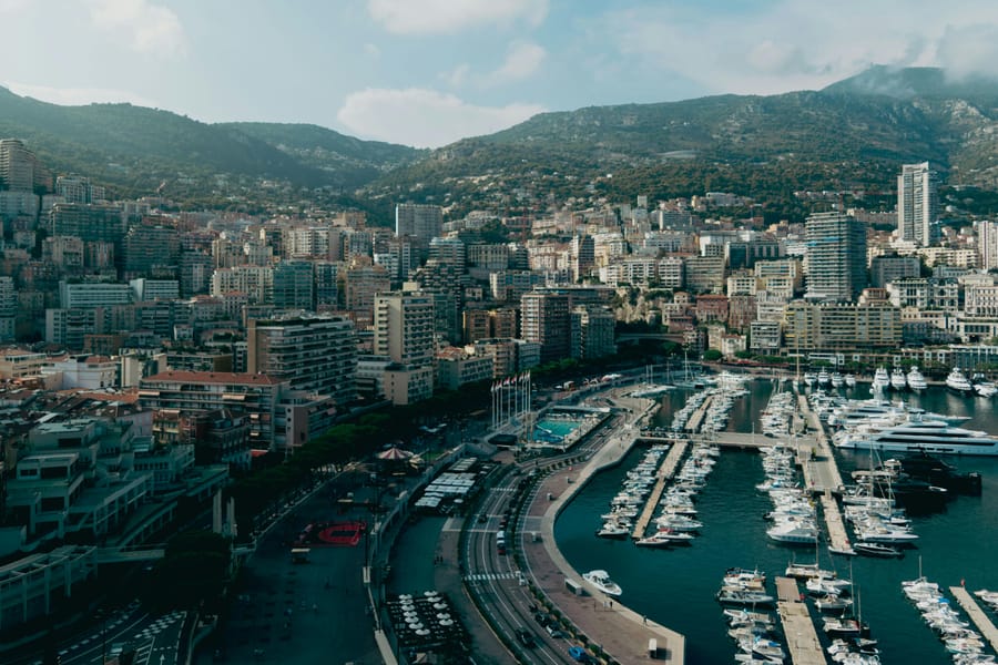 Aerial view of luxury yachts docked in Monaco's marina under blue skies.