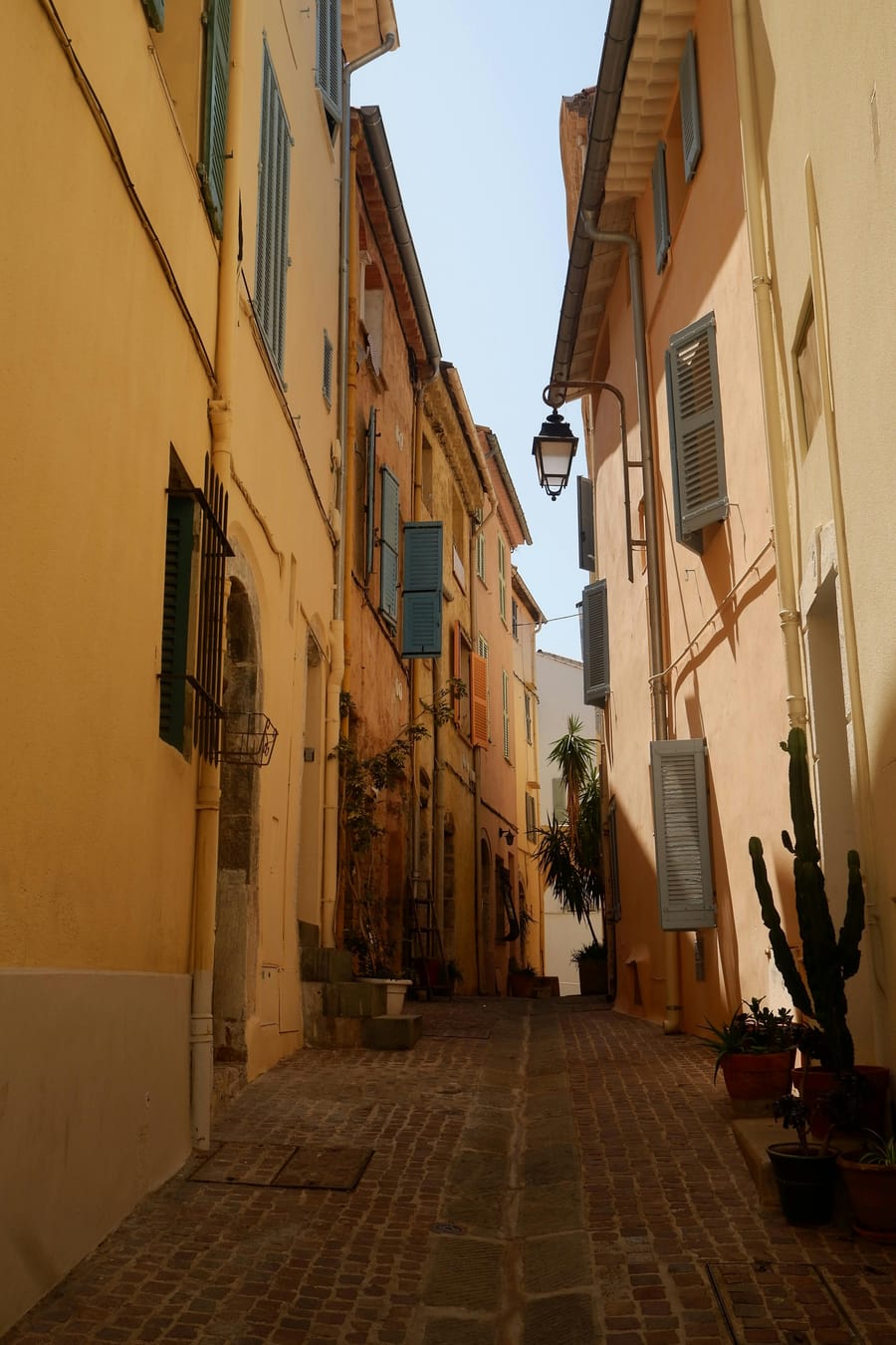 Narrow alley between vibrant buildings in a Côte d'Azur old town.