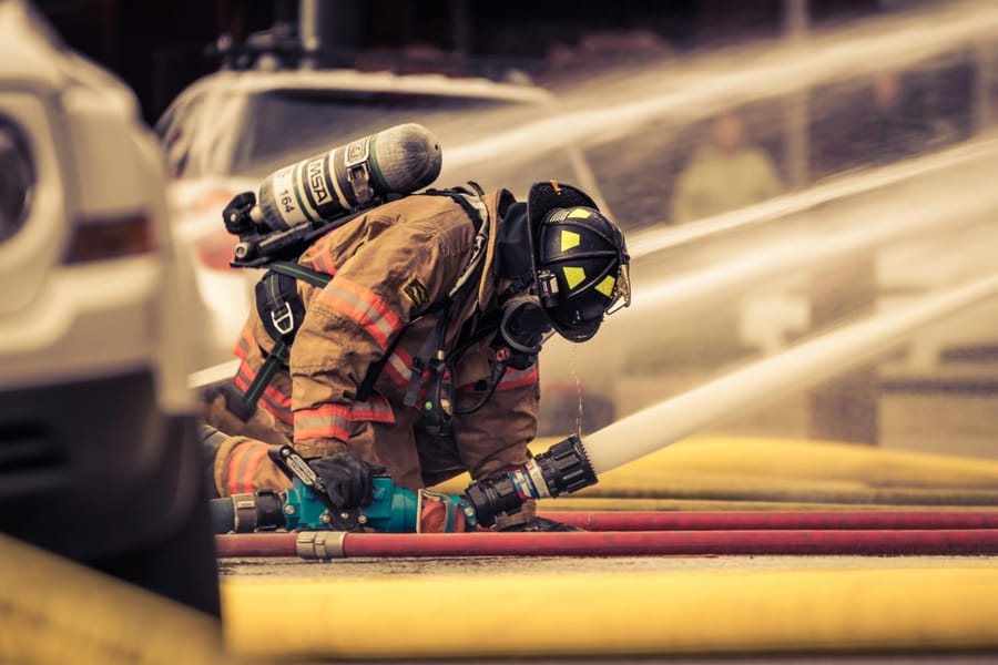 STCW student handling a water hose during outdoor emergency-response practice.